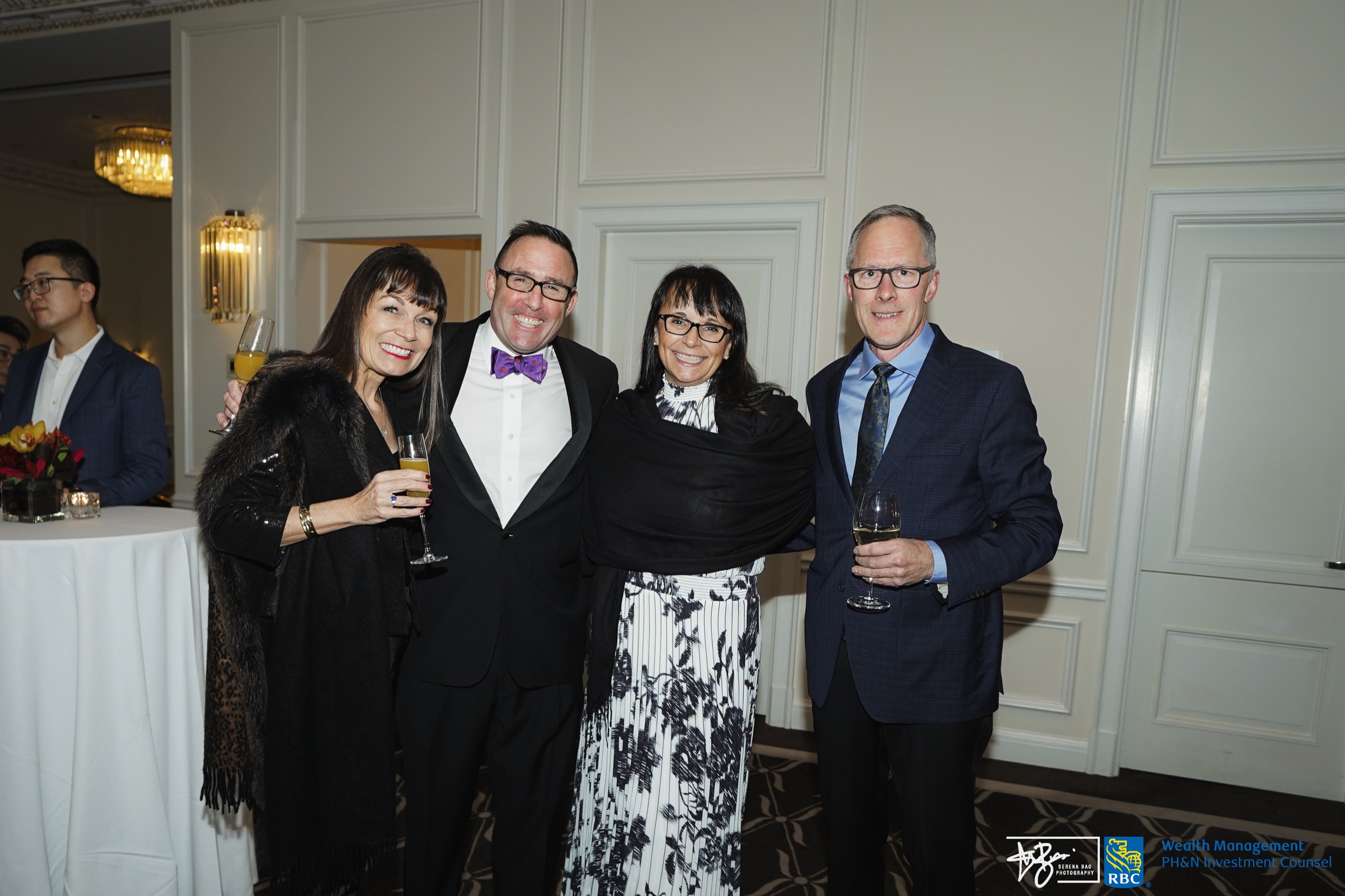 Four guests posing together at a catered event