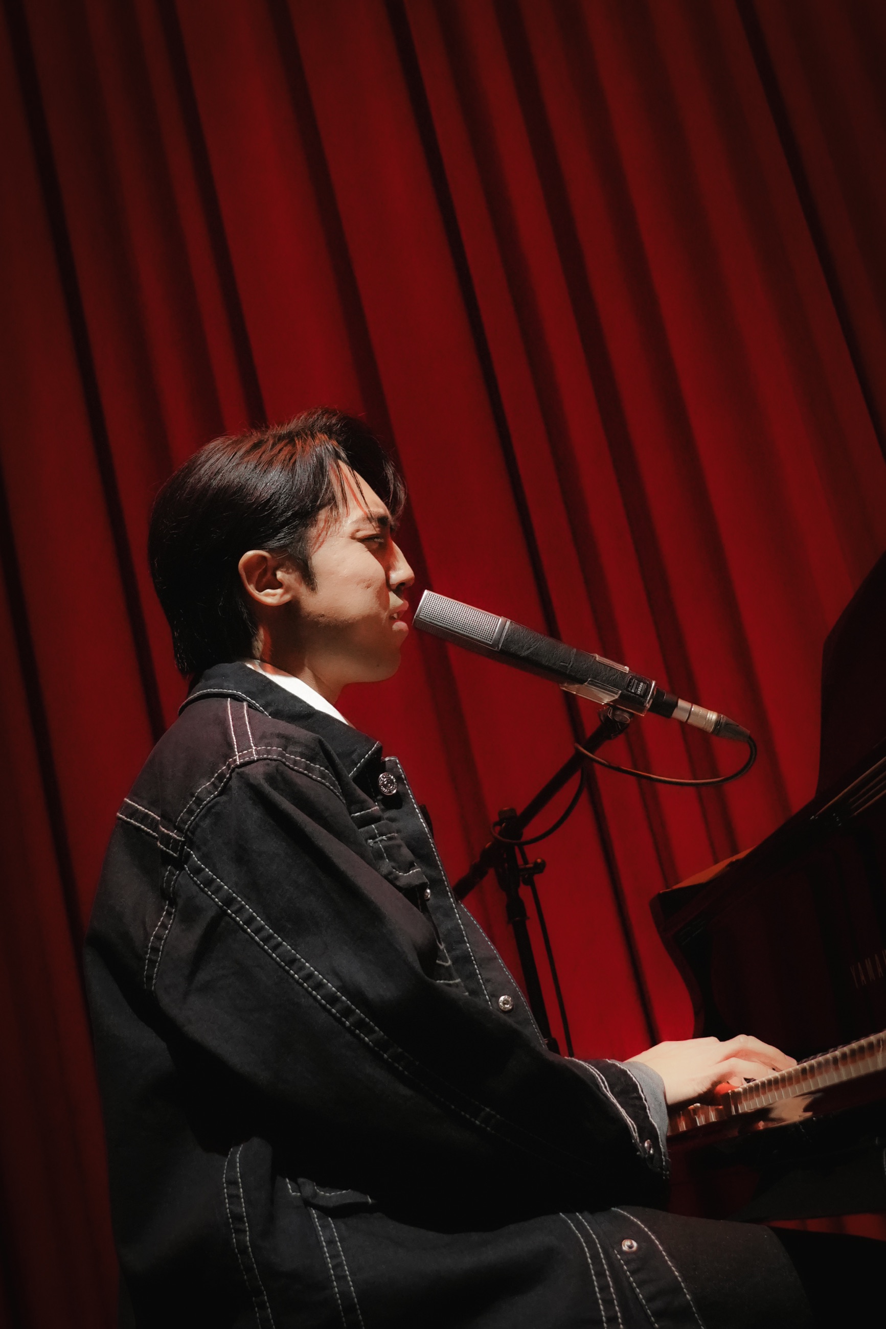 A pianist singing beneath red stage light