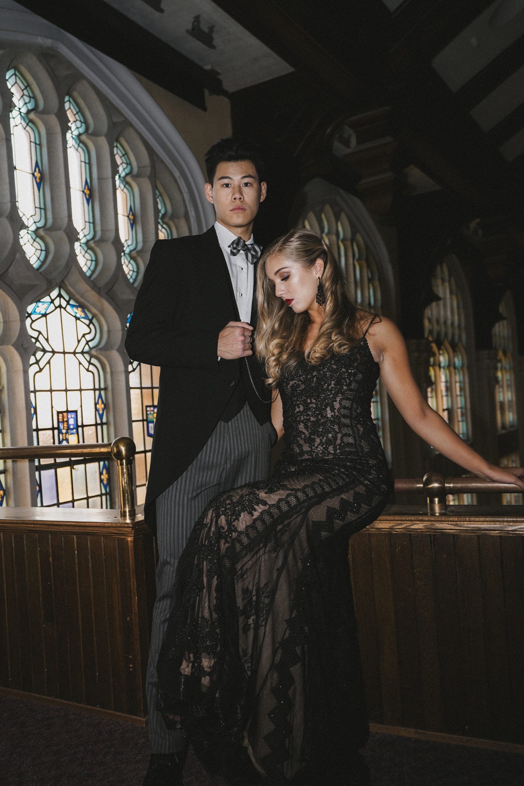 A couple in black eveningwear posing in a historic hall