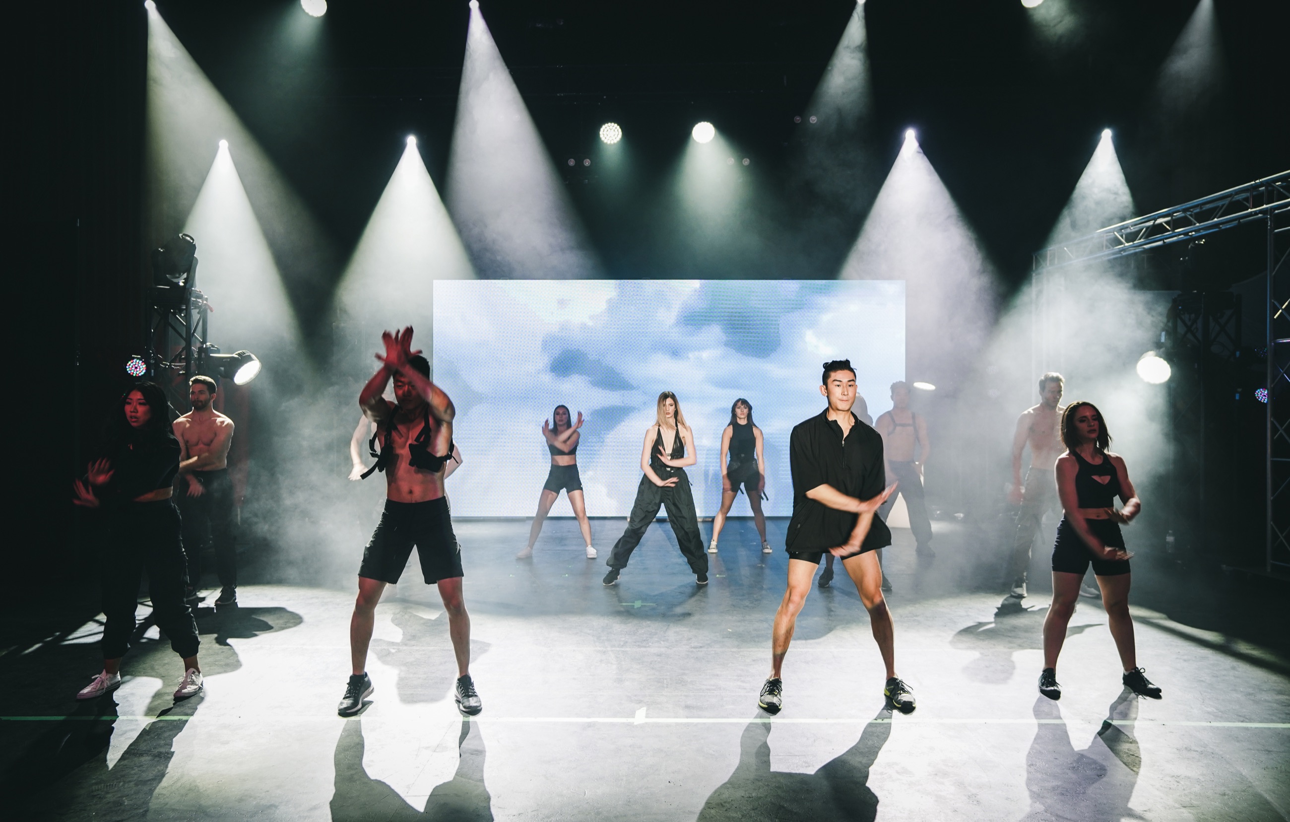 Fashion show performers moving beneath dramatic stage lighting