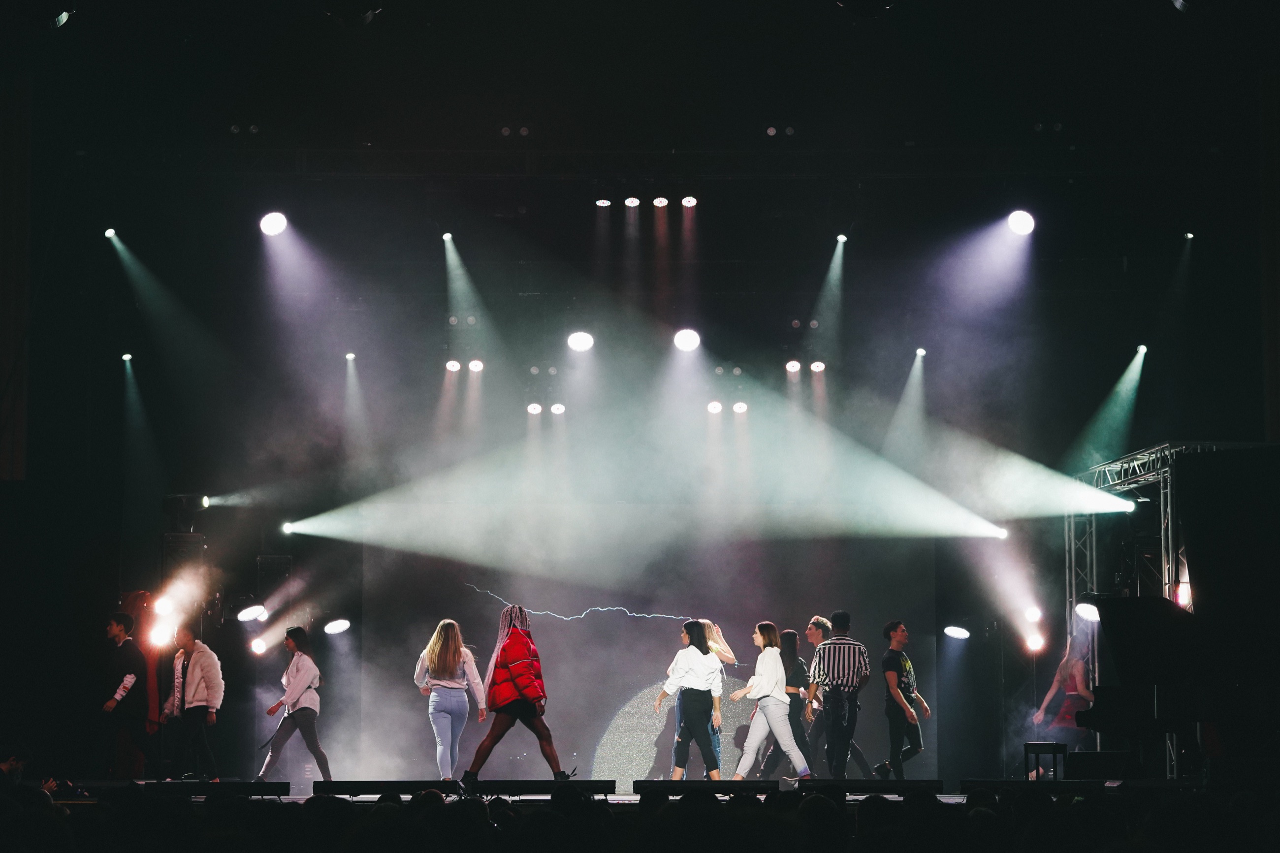 A wide view of performers crossing a brightly lit stage