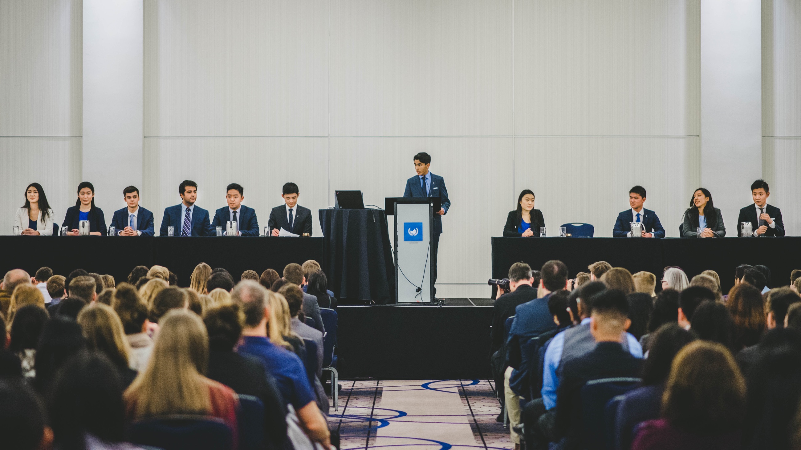 A conference panel and speaker addressing a full audience
